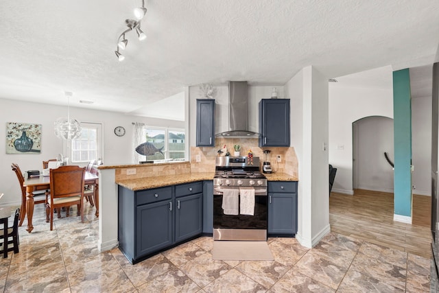 1126 Heathfield Dr, Channelview, TX 77530 - kitchen featuring wall chimney exhaust hood, stainless steel range with gas cooktop, arched walkways, a textured ceiling, and a peninsula