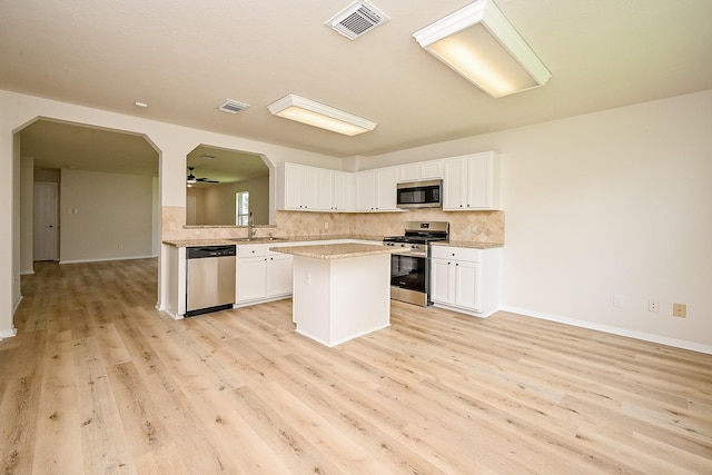 2046 Grand Park Dr, Missouri City, TX 77489 - kitchen featuring stainless steel appliances, tasteful backsplash, light wood-type flooring, and white cabinets