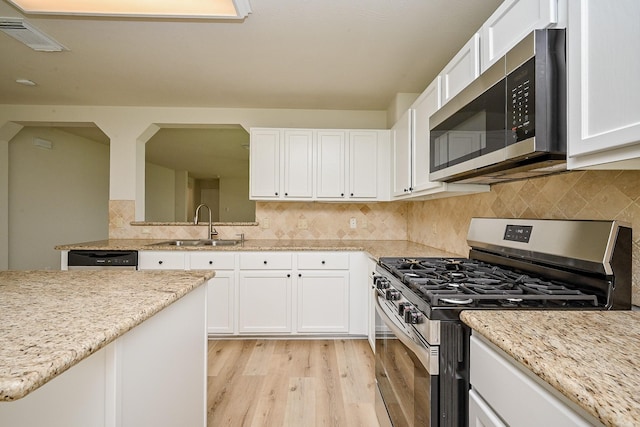 2046 Grand Park Dr, Missouri City, TX 77489 - kitchen featuring appliances with stainless steel finishes, light wood-style floors, white cabinets, tasteful backsplash, and light stone counters