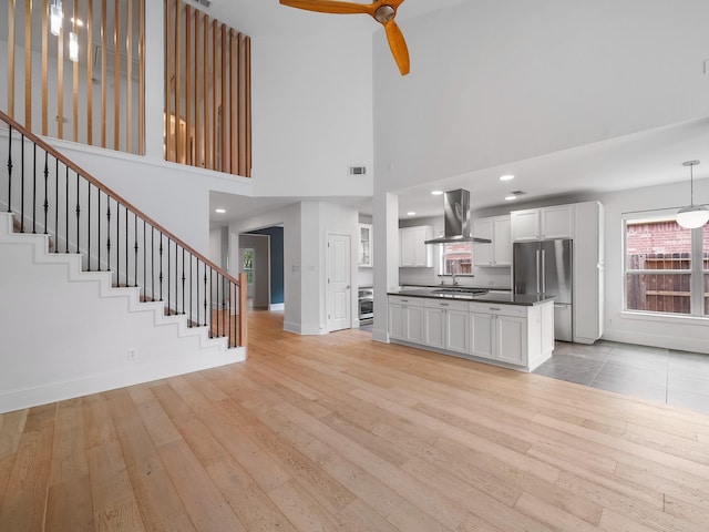 28111 Harper Creek Ln, Katy, TX 77494 - unfurnished living room with light wood-style floors, a towering ceiling, stairs, and plenty of natural light