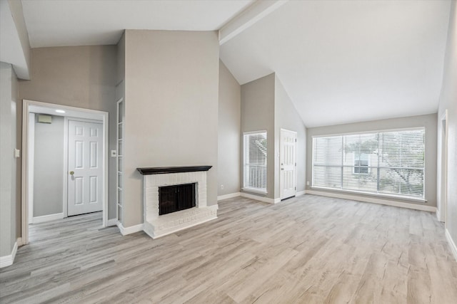 2100 Tanglewilde St Unit 360, Houston, TX 77063 - unfurnished living room featuring high vaulted ceiling, light wood-type flooring, a brick fireplace, and beamed ceiling