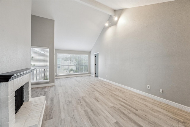 2100 Tanglewilde St Unit 360, Houston, TX 77063 - unfurnished living room with wood finished floors, beamed ceiling, a brick fireplace, a textured wall, and high vaulted ceiling
