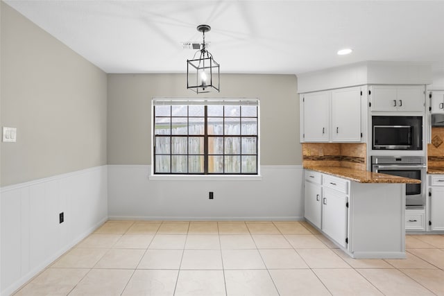3808 Montego Dr, Baytown, TX 77521 - kitchen featuring oven, built in microwave, wainscoting, light stone counters, and white cabinetry