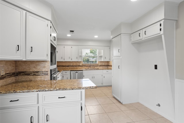 3808 Montego Dr, Baytown, TX 77521 - kitchen with appliances with stainless steel finishes, light stone countertops, tasteful backsplash, light tile patterned flooring, and white cabinets