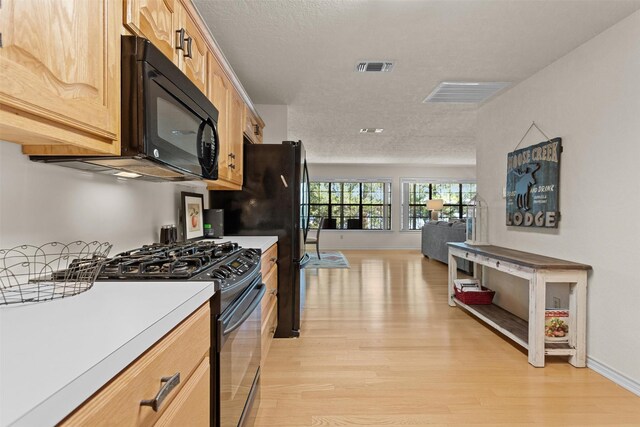 386 Dailey Rd, Crockett, TX 75835 - kitchen with black appliances, light wood-type flooring, light countertops, light brown cabinets, and a textured ceiling