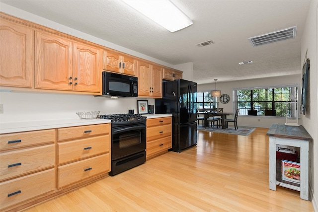 386 Dailey Rd, Crockett, TX 75835 - kitchen with black appliances, light wood-type flooring, light countertops, and hanging light fixtures