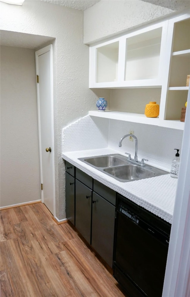 6410 Del Monte Dr Unit 118, Houston, TX 77057 - kitchen with black dishwasher, open shelves, light wood finished floors, light countertops, and a textured wall