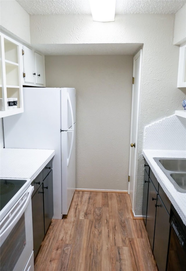 6410 Del Monte Dr Unit 118, Houston, TX 77057 - kitchen with dishwasher, electric stove, light wood-style flooring, light countertops, and white cabinetry