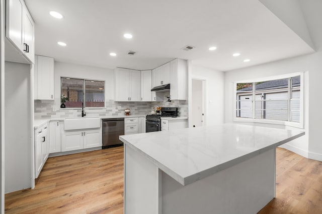 9030 Tanager St, Houston, TX 77036 - kitchen with appliances with stainless steel finishes, backsplash, light wood-style flooring, under cabinet range hood, and recessed lighting