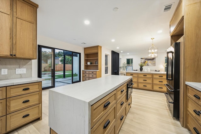 5005 Chestnut St, Bellaire, TX 77401 - kitchen with freestanding refrigerator, light wood-style floors, a center island, backsplash, and decorative light fixtures