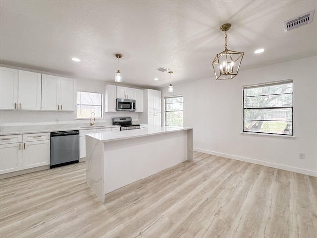 14214 Morinscott, Houston, TX 77049 - kitchen with stainless steel appliances, light wood-style flooring, light countertops, white cabinetry, and recessed lighting