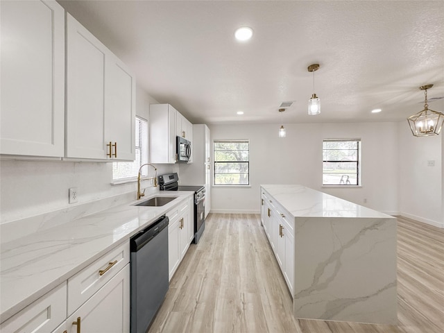14214 Morinscott, Houston, TX 77049 - kitchen featuring appliances with stainless steel finishes, light wood finished floors, a kitchen island, white cabinets, and recessed lighting