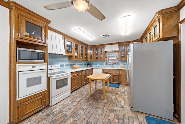 8105 Miller Dr, Hitchcock, TX 77563 - kitchen with white appliances, brown cabinets, backsplash, brick patterned flooring, and glass insert cabinets