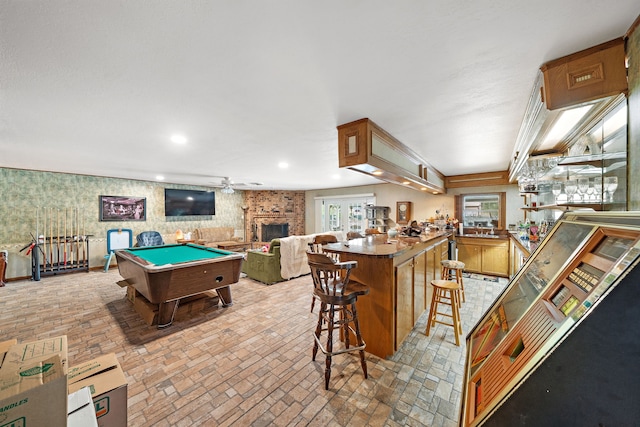 8105 Miller Dr, Hitchcock, TX 77563 - playroom featuring billiards table, brick patterned flooring, ceiling fan, wallpapered walls, and a large fireplace