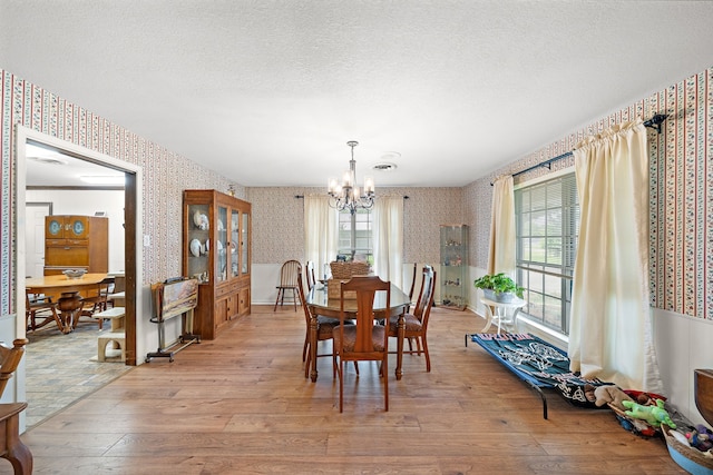 8105 Miller Dr, Hitchcock, TX 77563 - dining room featuring wallpapered walls, a chandelier, light wood-style flooring, plenty of natural light, and a textured ceiling
