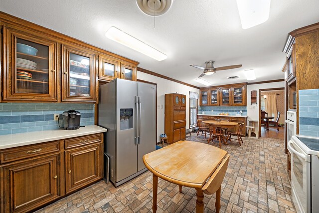 8105 Miller Dr, Hitchcock, TX 77563 - kitchen with white appliances, brick patterned flooring, decorative backsplash, ornamental molding, and brown cabinets