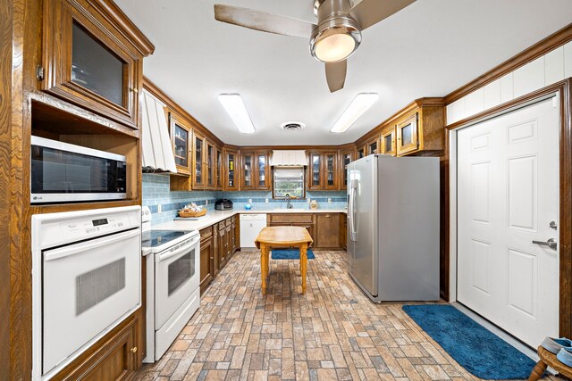 8105 Miller Dr, Hitchcock, TX 77563 - kitchen with appliances with stainless steel finishes, decorative backsplash, brown cabinetry, and light countertops
