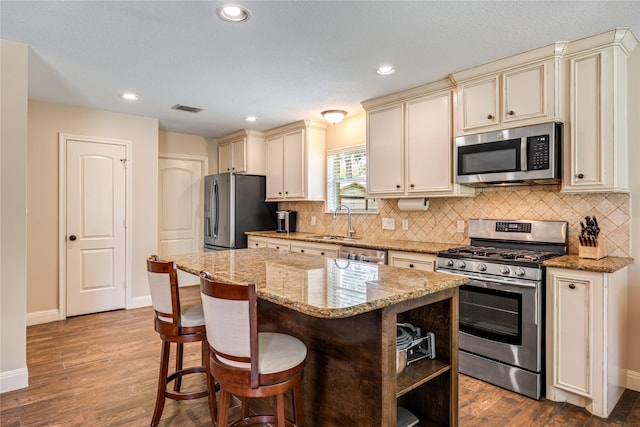 2546 Anzalone Dr, Spring, TX 77373 - kitchen featuring stainless steel appliances, cream cabinets, wood finished floors, a center island, and tasteful backsplash