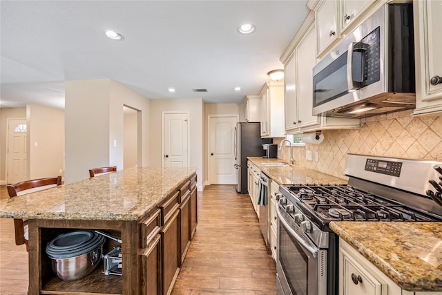 2546 Anzalone Dr, Spring, TX 77373 - kitchen featuring stainless steel appliances, light wood finished floors, cream cabinetry, a kitchen island, and recessed lighting