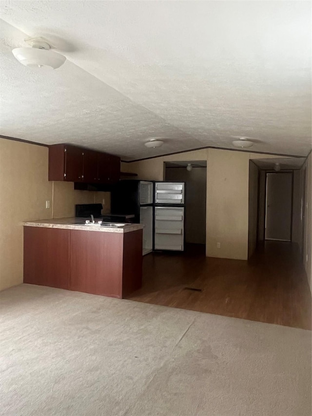 16906 Balmoral, Montgomery, TX 77316 - kitchen featuring a peninsula, dark colored carpet, freestanding refrigerator, a textured ceiling, and light countertops