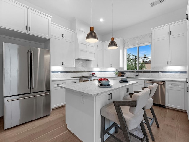 5240 Cornish Unit B, Houston, TX 77007 - kitchen with appliances with stainless steel finishes, a breakfast bar, light wood-style floors, white cabinets, and recessed lighting