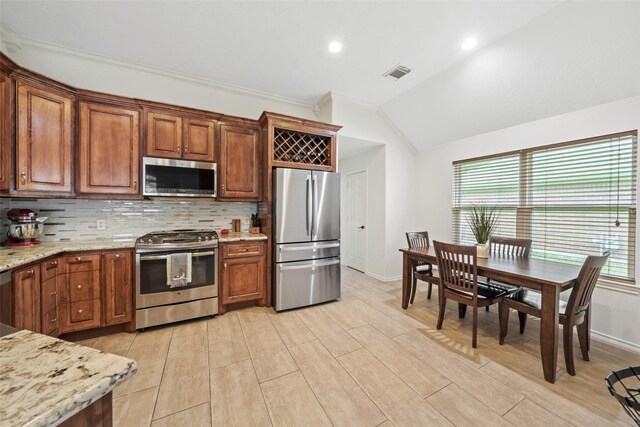 5207 Caprock Dr, Pearland, TX 77584 - kitchen with stainless steel appliances, lofted ceiling, tasteful backsplash, light stone countertops, and brown cabinets
