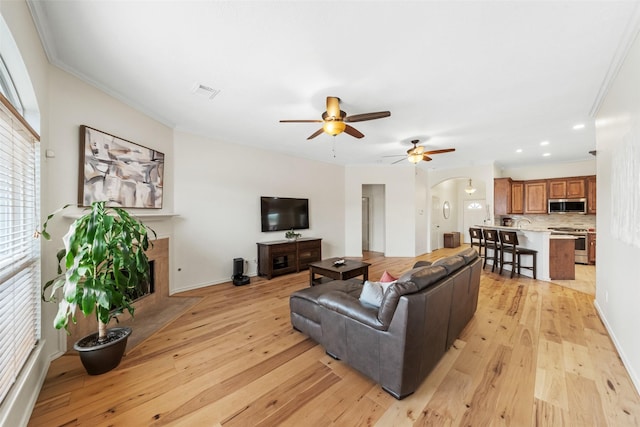 5207 Caprock Dr, Pearland, TX 77584 - living area featuring arched walkways, light wood-type flooring, ceiling fan, a fireplace with flush hearth, and recessed lighting