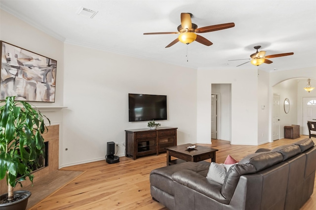 5207 Caprock Dr, Pearland, TX 77584 - living area featuring a ceiling fan, arched walkways, ornamental molding, light wood-type flooring, and a fireplace with flush hearth