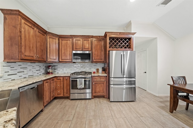 5207 Caprock Dr, Pearland, TX 77584 - kitchen with stainless steel appliances, crown molding, light stone counters, light wood finished floors, and decorative backsplash