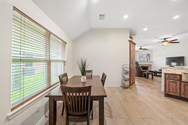 5207 Caprock Dr, Pearland, TX 77584 - dining area featuring a fireplace, ceiling fan, recessed lighting, lofted ceiling, and light wood-type flooring