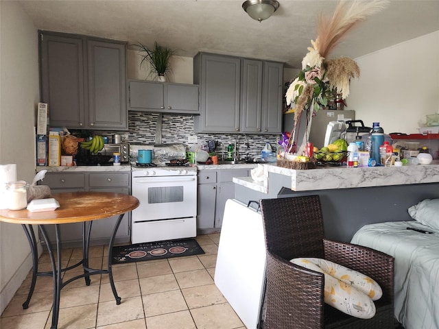 1902 July St, Houston, TX 77093 - kitchen with gas range gas stove, gray cabinets, backsplash, light countertops, and light tile patterned floors