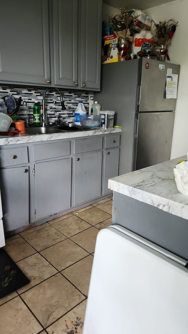 1902 July St, Houston, TX 77093 - kitchen featuring freestanding refrigerator, decorative backsplash, light tile patterned flooring, and gray cabinetry