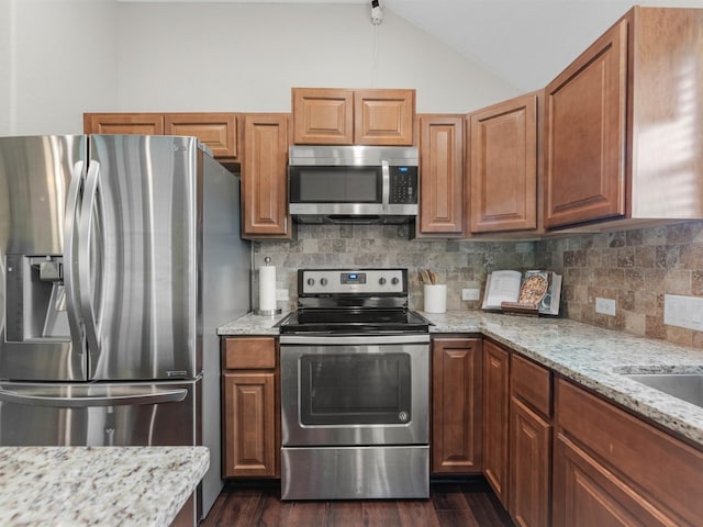 70 Rd 22705, Cleveland, TX 77327 - kitchen with stainless steel appliances, vaulted ceiling, dark wood-style flooring, backsplash, and light stone counters