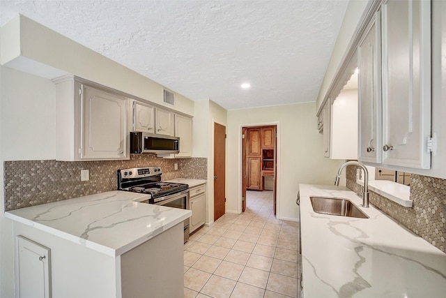 3507 Dawnwood Dr, Spring, TX 77380 - kitchen featuring stainless steel appliances, light stone countertops, backsplash, light tile patterned floors, and a textured ceiling