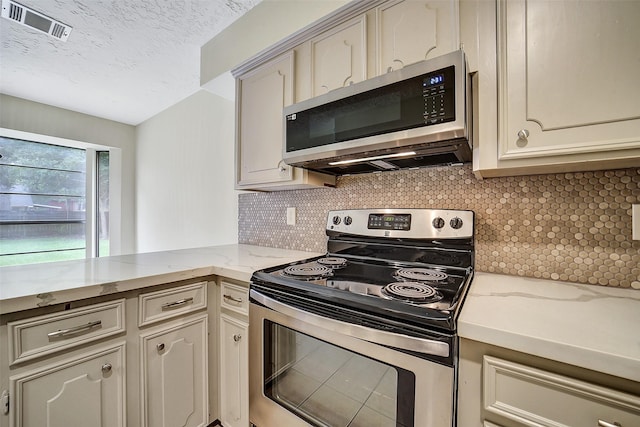 3507 Dawnwood Dr, Spring, TX 77380 - kitchen featuring stainless steel appliances, backsplash, a textured ceiling, and light stone countertops