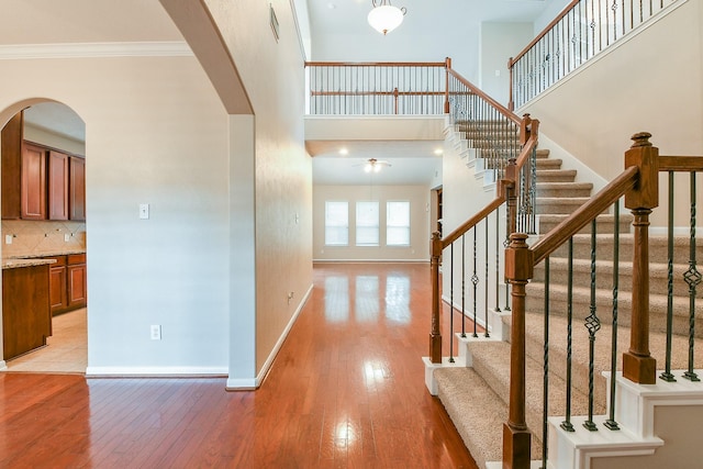 14307 Baron Creek Ln, Houston, TX 77044 - entryway featuring arched walkways, light wood-style flooring, ceiling fan, crown molding, and stairway