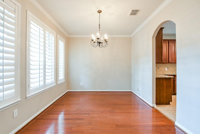 14307 Baron Creek Ln, Houston, TX 77044 - unfurnished dining area featuring light wood-type flooring, arched walkways, ornamental molding, and a chandelier