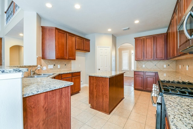 14307 Baron Creek Ln, Houston, TX 77044 - kitchen featuring stainless steel appliances, arched walkways, light stone countertops, backsplash, and recessed lighting