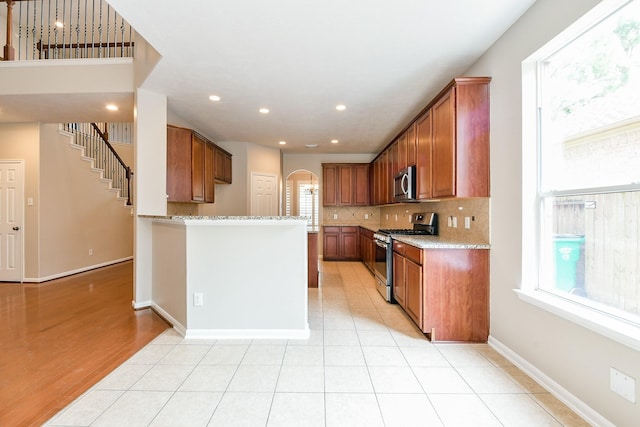 14307 Baron Creek Ln, Houston, TX 77044 - kitchen with appliances with stainless steel finishes, arched walkways, tasteful backsplash, brown cabinets, and recessed lighting