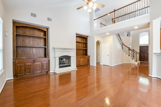 14307 Baron Creek Ln, Houston, TX 77044 - unfurnished living room with ceiling fan, high vaulted ceiling, built in features, a fireplace with raised hearth, and arched walkways