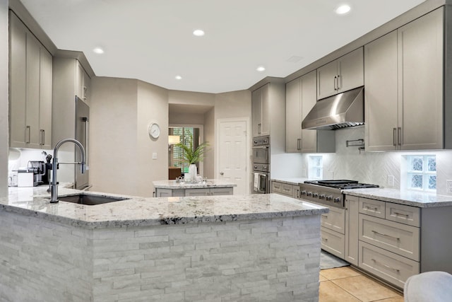 4502 Buffalo Lake Ct, Richmond, TX 77406 - kitchen featuring under cabinet range hood, gray cabinetry, a center island, light stone counters, and backsplash