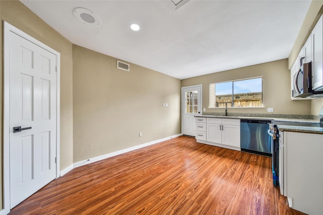 6401 Deihl Rd Unit 901, Houston, TX 77092 - kitchen featuring stainless steel appliances, white cabinets, light wood-type flooring, and dark stone counters