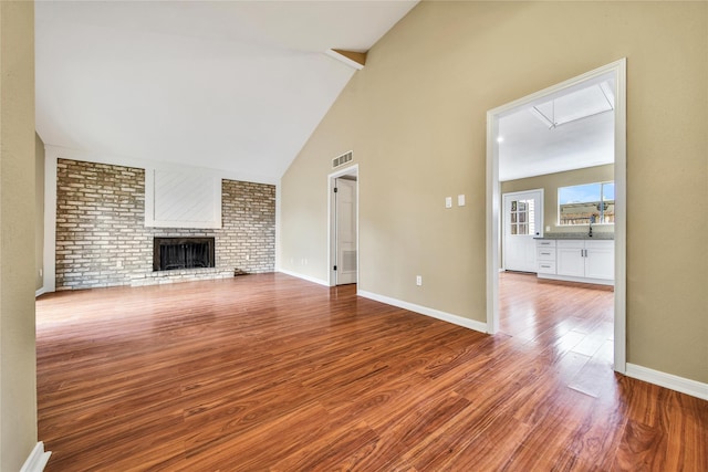 6401 Deihl Rd Unit 901, Houston, TX 77092 - unfurnished living room featuring wood finished floors, a brick fireplace, and high vaulted ceiling