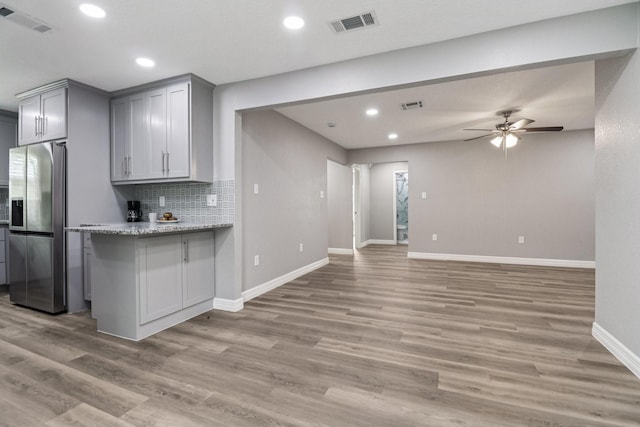 16820 Laurelwood Dr, Channelview, TX 77530 - kitchen with stainless steel fridge with ice dispenser, gray cabinets, ceiling fan, tasteful backsplash, and light wood-style floors