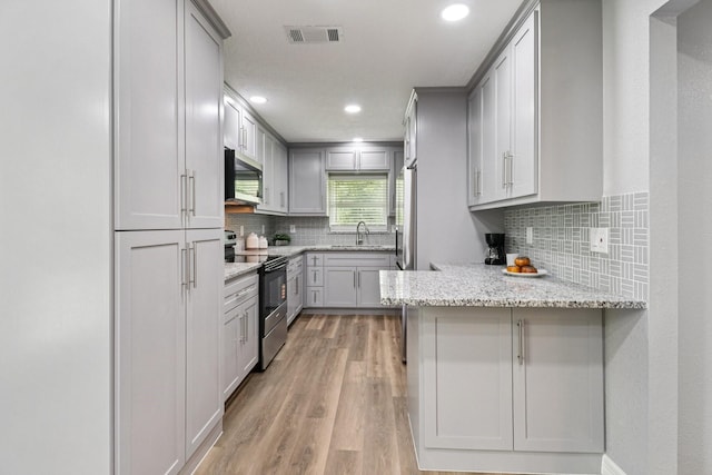 16820 Laurelwood Dr, Channelview, TX 77530 - kitchen featuring stainless steel appliances, a peninsula, recessed lighting, light wood-type flooring, and light stone countertops