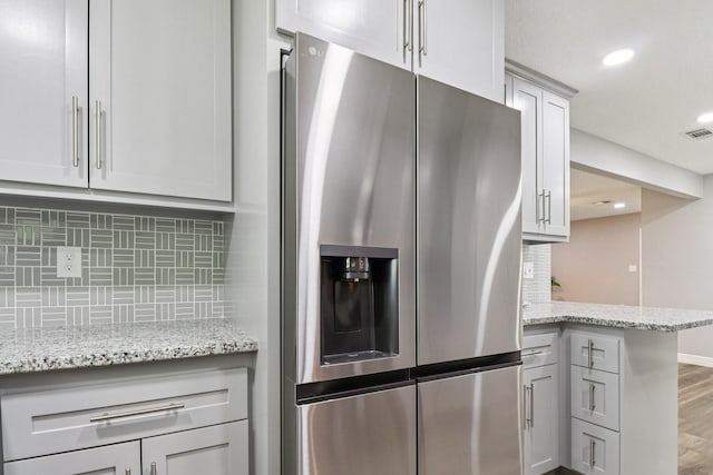 16820 Laurelwood Dr, Channelview, TX 77530 - kitchen featuring stainless steel fridge with ice dispenser, tasteful backsplash, wood finished floors, light stone counters, and recessed lighting