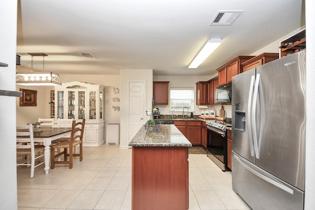 38327 Miranda Ln, Magnolia, TX 77355 - kitchen with appliances with stainless steel finishes, a kitchen island, dark stone countertops, and light tile patterned floors
