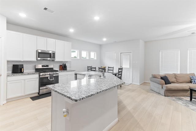 214 Water Grass Trl, Clute, TX 77531 - kitchen with stainless steel appliances, light wood-style floors, white cabinetry, light stone counters, and recessed lighting