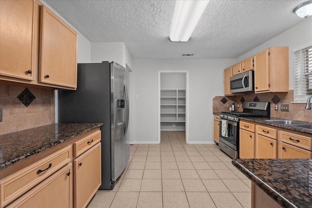 1726 Kemah Oaks Dr, Kemah, TX 77565 - kitchen featuring stainless steel appliances, decorative backsplash, a textured ceiling, light tile patterned flooring, and dark stone counters