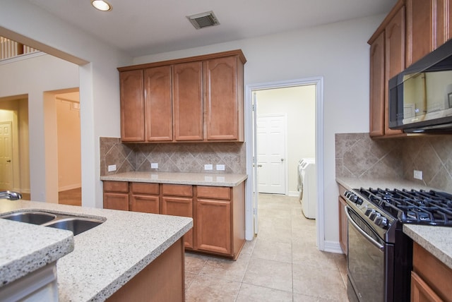 28015 Silverstream Ct, Fulshear, TX 77441 - kitchen featuring appliances with stainless steel finishes, light stone countertops, light tile patterned floors, washer / clothes dryer, and backsplash